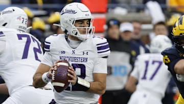 Nov 23, 2024; Ann Arbor, Michigan, USA;  Northwestern Wildcats quarterback Jack Lausch (12) drops back to pass against the Michigan Wolverines in the first half at Michigan Stadium. Mandatory Credit: Rick Osentoski-Imagn Images