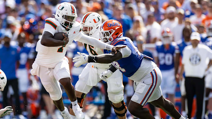 Aug 31, 2024; Gainesville, Florida, USA; Miami Hurricanes quarterback Cam Ward (1) runs past Florida Gators defensive lineman Caleb Banks (88) during the first half at Ben Hill Griffin Stadium. Mandatory Credit: Matt Pendleton-Imagn Images