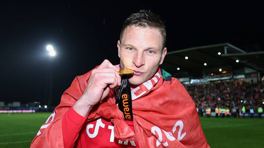 Paul Mullin kisses his champions winner medal as Wrexham celebrate promotion back to the English Football League.