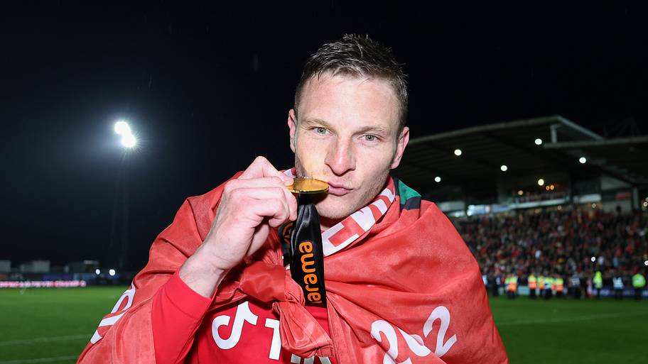 Paul Mullin kisses his champions winner medal as Wrexham celebrate promotion back to the English Football League.