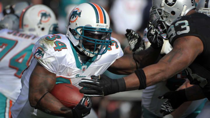 Miami Dolphins running back Ricky Williams (34) is pursued by Oakland Raiders defensive tackle Tommy Kellly (93) at the Oakland-Alameda County Coliseum in 2010.