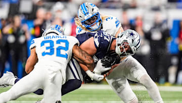Detroit Lions safety Brian Branch (32) and linebacker Alex Anzalone (34) tackle Dallas Cowboys tight end Jake Ferguson (87) during the first half at Ford Field in Detroit on Thursday, Dec. 4, 2025.