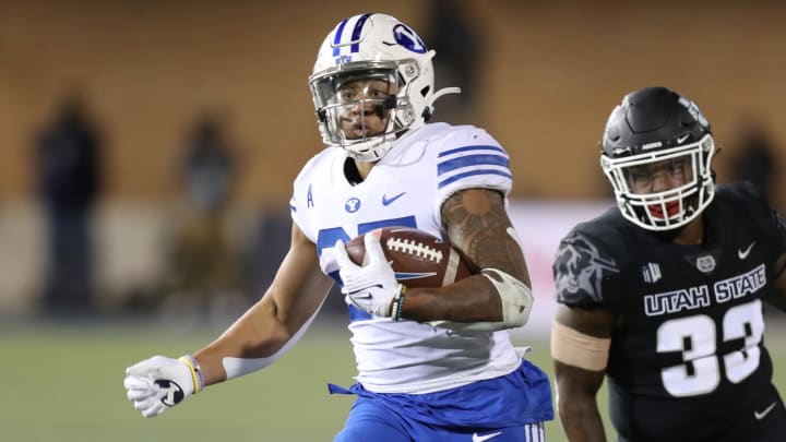 Oct 1, 2021; Logan, Utah, USA; Brigham Young Cougars running back Tyler Allgeier (25) is pursued by Utah State Aggies linebacker Kevin Meitzenheimer (33) during the third quarter at Merlin Olsen Field at Maverik Stadium. Mandatory Credit: Rob Gray-USA TODAY Sports