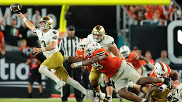 Aug 31, 2025; Miami Gardens, Florida, USA; Notre Dame Fighting Irish quarterback CJ Carr (13) throws the ball to avoid a sack against the Miami Hurricanes at Hard Rock Stadium. Mandatory Credit: Sam Navarro-Imagn Images