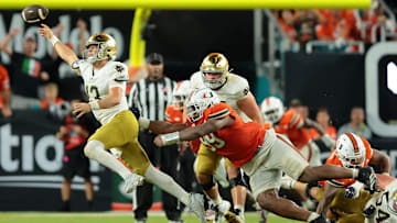 Aug 31, 2025; Miami Gardens, Florida, USA; Notre Dame Fighting Irish quarterback CJ Carr (13) throws the ball to avoid a sack against the Miami Hurricanes at Hard Rock Stadium. Mandatory Credit: Sam Navarro-Imagn Images