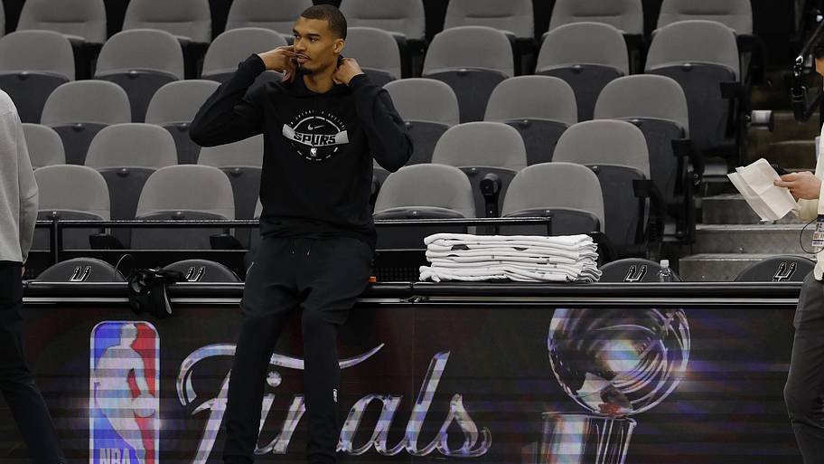 Victor Wembanyama sits at the scorer's table during Spurs practice on Media Day for the 2026 NBA Finals