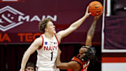 Dec 15, 2024; Blacksburg, Virginia, USA; Navy Midshipmen guard Austin Benigni (1) blocks the shot of Virginia Tech Hokies guard Ben Hammond (11) during the second half at Cassell Coliseum. Mandatory Credit: Peter Casey-Imagn Images