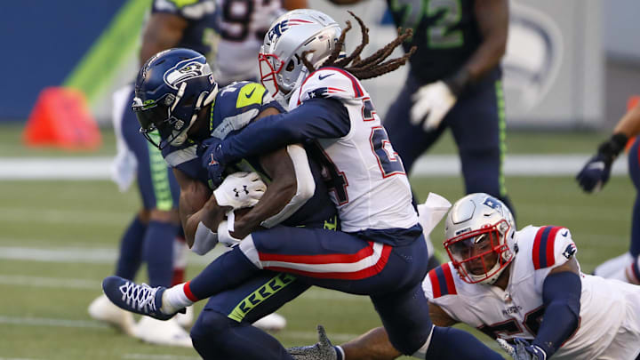 Sep 20, 2020; Seattle, Washington, USA; Seattle Seahawks wide receiver DK Metcalf (14) is tackled by New England Patriots cornerback Stephon Gilmore (24) and New England Patriots linebacker Anfernee Jennings (58) after making a reception during the second quarter at CenturyLink Field.