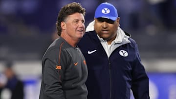 Oct 18, 2024; Provo, Utah, USA; Oklahoma State Cowboys head coach Mike Gundy (left) and Brigham Young Cougars head coach Kalani Sitake speak before the game at LaVell Edwards Stadium. Mandatory Credit: Rob Gray-Imagn Images
