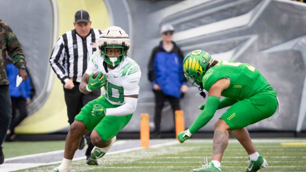 Oregon White Team running back Jordan James looks for a gap under cover from defensive back Kobe Savage