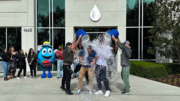 Niagara team members dump water coolers on UCLA Bruins college basketball water boy for NIL Deal in front of headquarters.