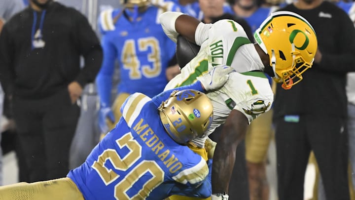 Sep 28, 2024; Pasadena, California, USA; UCLA Bruins linebacker Kain Medrano (20) brings down Oregon Ducks wide receiver Traeshon Holden (1) during the fourth quarter at Rose Bowl. Mandatory Credit: Robert Hanashiro-Imagn Images