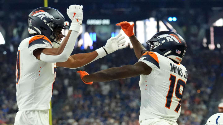 Denver Broncos wide receiver Devaughn Vele (81) and wide receiver Marvin Mims Jr. (19) celebrate a touchdown as Indianapolis Colts safety Nick Cross (20) looks on during the first half of a preseason game Sunday, Aug. 11, 2024, at Lucas Oil Stadium in Indianapolis.