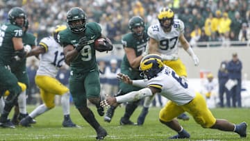 Oct 30, 2021; East Lansing, Michigan, USA; Michigan State Spartans running back Kenneth Walker III (9) runs past Michigan Wolverines defensive back R.J. Moten (6) for a touchdown during the fourth quarter at Spartan Stadium. Mandatory Credit: Raj Mehta-Imagn Images