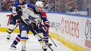 Dec 7, 2024; Edmonton, Alberta, CAN; St. Louis Blues defensemen Scott Perunovich (48) clears the puck against Edmonton Oilers forward Mattias Janmark (13) during the third period at Rogers Place. Mandatory Credit: Perry Nelson-Imagn Images