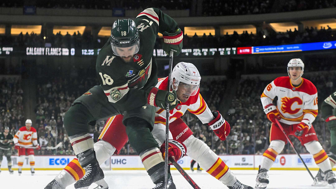 Jan 29, 2026; Saint Paul, Minnesota, USA;  Minnesota Wild forward Vinnie Hinostroza (18) protects the puck from Calgary Flames defensemen Kevin Bahl (7) during the third period at Grand Casino Arena. Mandatory Credit: Nick Wosika-Imagn Images