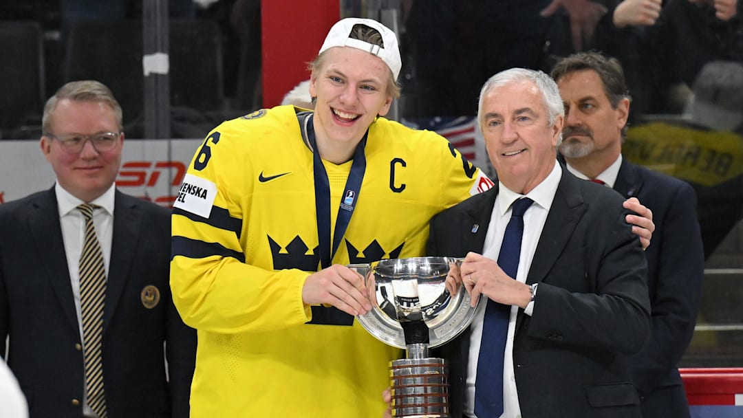 Jan 5, 2026; St. Paul, Minnesota, USA; Sweden forward Jack Berglund (26) is presented with the first place trophy by IIHF President Luc Tardif after defeating Czechia in the final of the 2026 IIHF World Junior Championship ice hockey tournament at Grand Casino Arena.