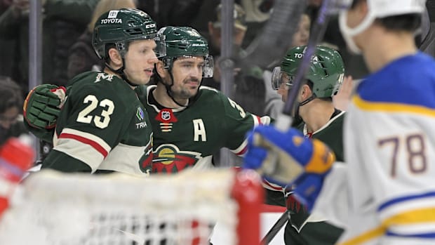 Hockey players in green uniform celebrate a goal score