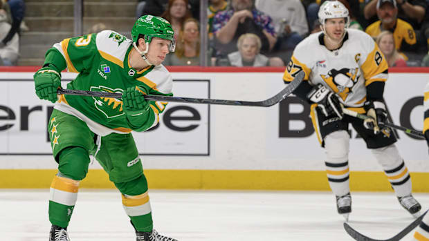 Hockey player in green uniform shoots the puc