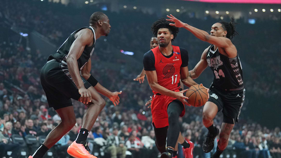 Apr 6, 2025; Portland, Oregon, USA; Portland Trail Blazers shooting guard Shaedon Sharpe (17) drives for the basket between San Antonio Spurs center Bismack Biyombo (18) and shooting guard Devin Vassell (24) during the first half at Moda Center. Mandatory Credit: Soobum Im-Imagn Images