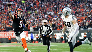 Jan 15, 2022; Cincinnati, OH, USA;  Cincinnati Bengals quarterback Joe Burrow (9) throws as Las Vegas Raiders defensive end Maxx Crosby (98) pressures in the second quarter during an NFL AFC wild-card playoff game, Saturday, Jan. 15, 2022, at Paul Brown Stadium in Cincinnati. Mandatory Credit: Kareem Elgazzar-Imagn Images
