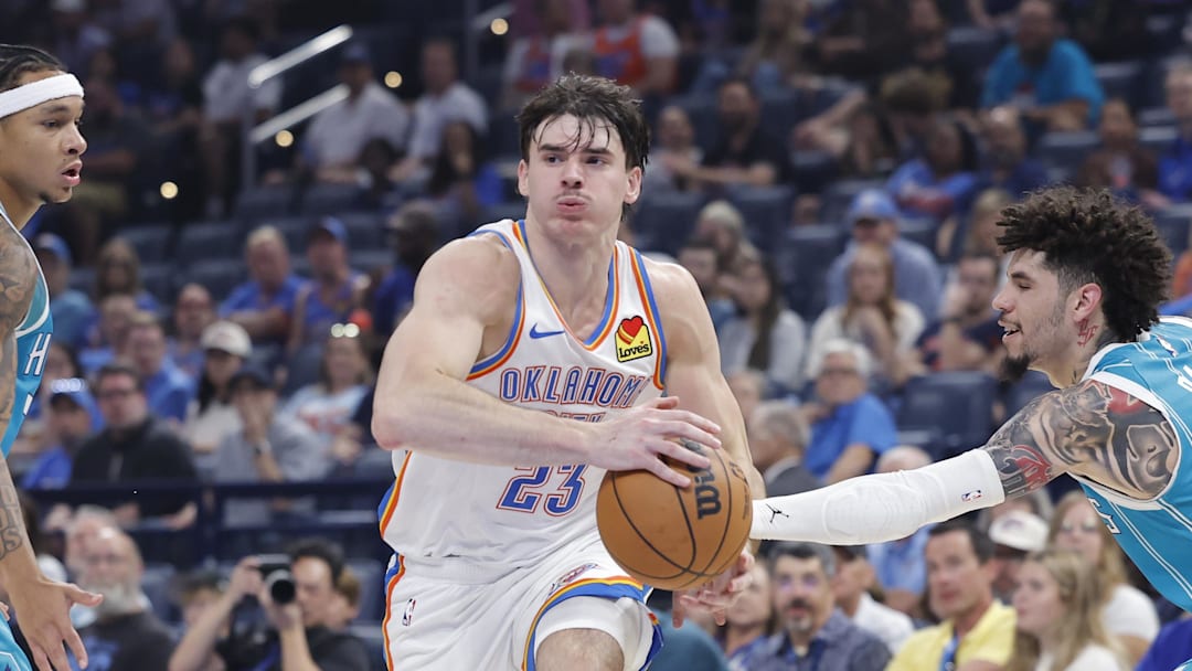 Oct 9, 2025; Oklahoma City, Oklahoma, USA; Oklahoma City Thunder guard Brooks Barnhizer (23) drives between Charlotte Hornets guard Tre Mann (23) and guard Lamelo Ball (1) during the second quarter of a game between the Charlotte Hornets and the Oklahoma City Thunder at Paycom Center. Mandatory Credit: Alonzo Adams-Imagn Images