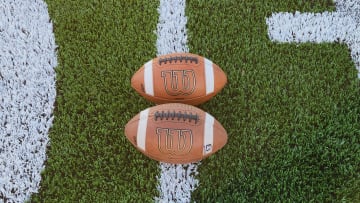 Two Wilson footballs on a football field 