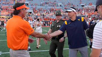 Oklahoma State coach Mike Gundy, left, shakes hands with West Virginia coach Neal Brown after a college football game between the Oklahoma State Cowboys (OSU) and the West Virginia Mountaineers at Boone Pickens Stadium in Stillwater, Okla., Saturday, Oct. 5, 2024.