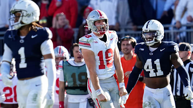 Ohio State Buckeyes quarterback Will Howard celebrates a first-down run beside Penn State Nittany Lions linebacker Kobe King.