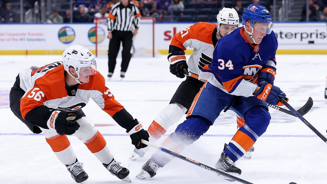Sep 27, 2023; Elmont, New York, USA; New York Islanders defenseman Paul LaDue (34) controls the puck against Philadelphia Flyers right wing Samu Tuomaala (56) and center Scott Laughton (21) and left wing Noah Cates (27) during the first period at UBS Arena. Mandatory Credit: Brad Penner-Imagn Images