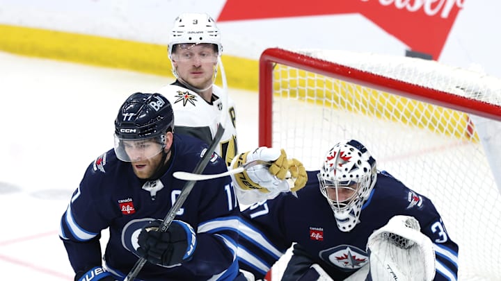 Mar 24, 2026; Winnipeg, Manitoba, CAN; Winnipeg Jets center Adam Lowry (17) and Vegas Golden Knights center Jack Eichel (9) tie up sticks in front of Winnipeg Jets goaltender Connor Hellebuyck (37) in the third period at Canada Life Centre. Mandatory Credit: James Carey Lauder-Imagn Images