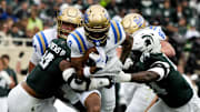 Oct 11, 2025; East Lansing, Michigan, USA; UCLA Bruins running back Jalen Berger (0) runs through the Michigan State defense in the second quarter at Spartan Stadium.
