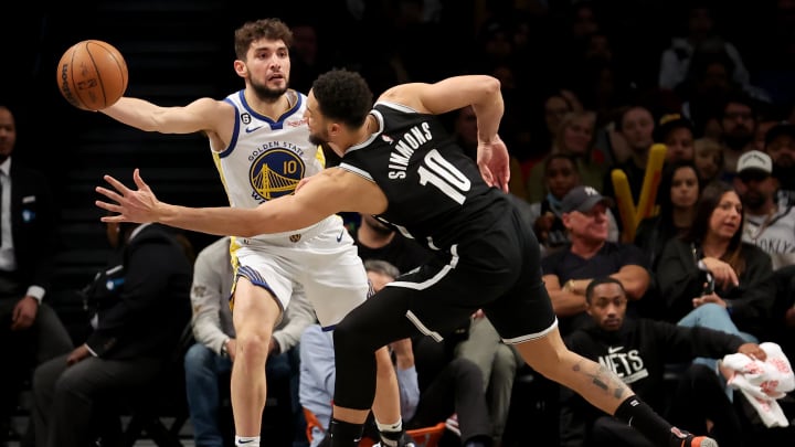Dec 21, 2022; Brooklyn, New York, USA; Golden State Warriors guard Ty Jerome (10) passes the ball around Brooklyn Nets guard Ben Simmons (10) during the third quarter at Barclays Center. Mandatory Credit: Brad Penner-USA TODAY Sports