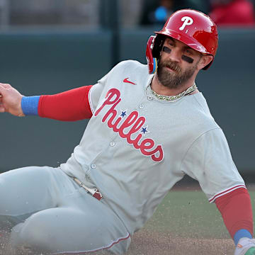 Philadelphia Phillies star Bryce Harper slides into home plate to score a run.