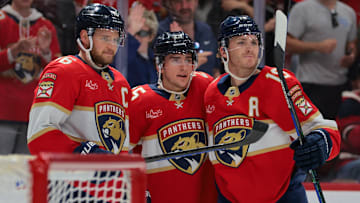 Nov 30, 2024; Sunrise, Florida, USA; Florida Panthers right wing Mackie Samoskevich (center) celebrates with center Aleksander Barkov (left) and left wing Matthew Tkachuk (right) after scoring against the Carolina Hurricanes during the second period at Amerant Bank Arena. Mandatory Credit: Sam Navarro-Imagn Images