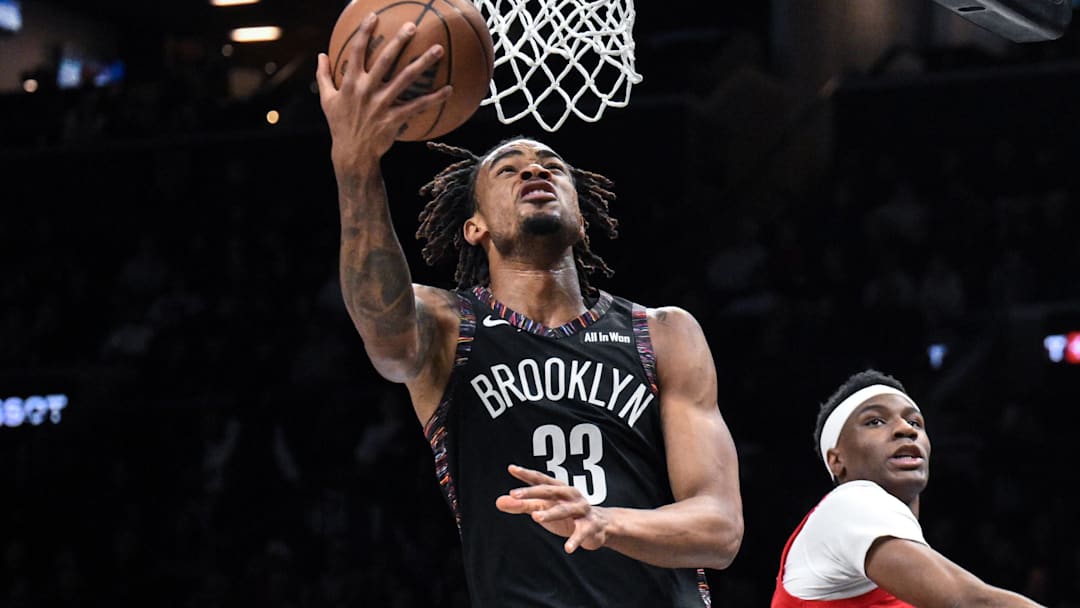 Dec 21, 2025; Brooklyn, New York, USA; Brooklyn Nets center Nic Claxton (33) drives to the basket while defended by Toronto Raptors guard Ja'Kobe Walter (14) during the first half at Barclays Center. Mandatory Credit: John Jones-Imagn Images