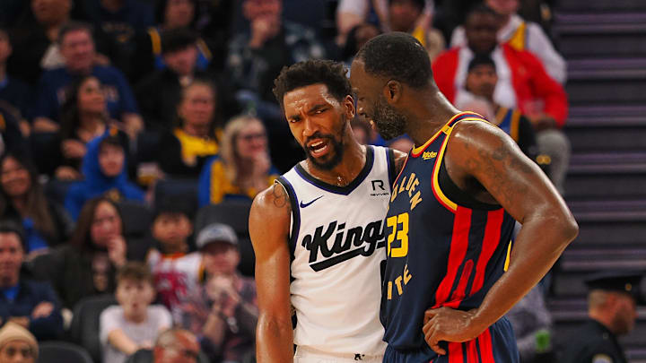 Jan 5, 2025; San Francisco, California, USA; Sacramento Kings guard Malik Monk (0) and Golden State Warriors forward Draymond Green (23) between plays during the third quarter at Chase Center. Mandatory Credit: Kelley L Cox-Imagn Images