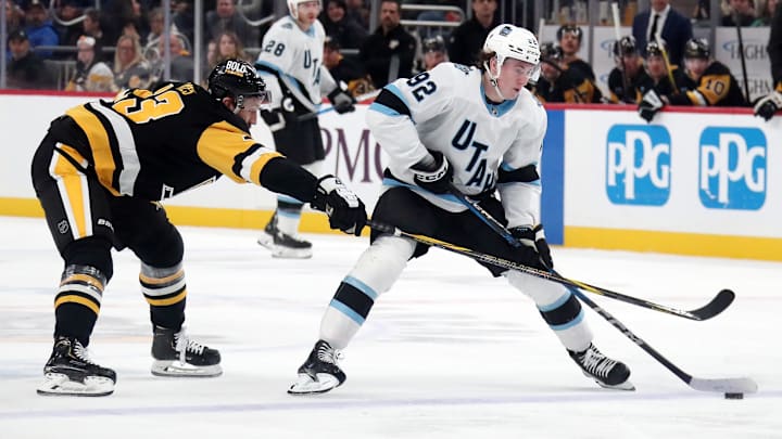 Nov 23, 2024; Pittsburgh, Pennsylvania, USA;  Utah Hockey Club center Logan Cooley (92) skates up ice with the puck against Pittsburgh Penguins right wing Kevin Hayes (13) during the second period at PPG Paints Arena. Mandatory Credit: Charles LeClaire-Imagn Images