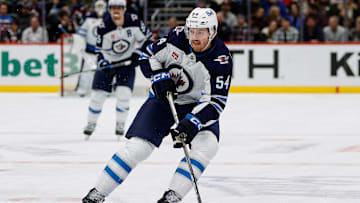 Jan 22, 2025; Denver, Colorado, USA; Winnipeg Jets defenseman Dylan Samberg (54) controls the puck in the first period against the Colorado Avalanche at Ball Arena. Mandatory Credit: Isaiah J. Downing-Imagn Images