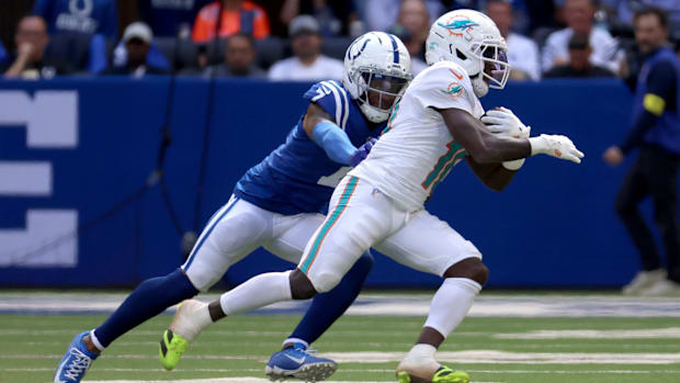 Colts cornerback Charvarius Ward (blue and white uniform) goes for a tackle on the ball carrier.