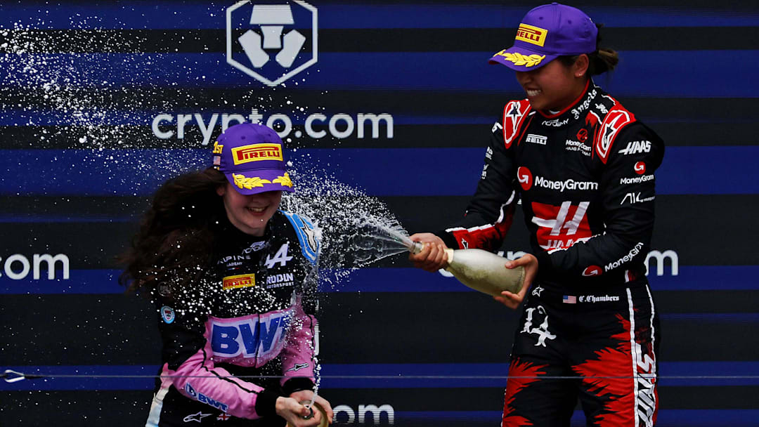 May 4, 2024; Miami Gardens, Florida, USA; F1 Academy driver Chloe Chambers (14) celebrates with F1 Academy driver Abbi Pulling (9) on the podium after the F1 Academy First Race at Miami International Autodrome. Pulling won first place and Chambers won third place. Mandatory Credit: Peter Casey-Imagn Images