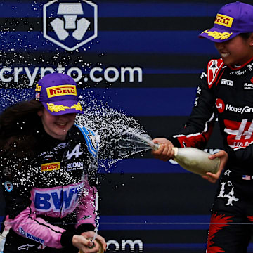 May 4, 2024; Miami Gardens, Florida, USA; F1 Academy driver Chloe Chambers (14) celebrates with F1 Academy driver Abbi Pulling (9) on the podium after the F1 Academy First Race at Miami International Autodrome. Pulling won first place and Chambers won third place. Mandatory Credit: Peter Casey-Imagn Images