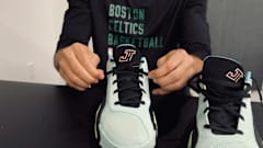 Jayson Tatum ties his green Jordan Brand sneakers.