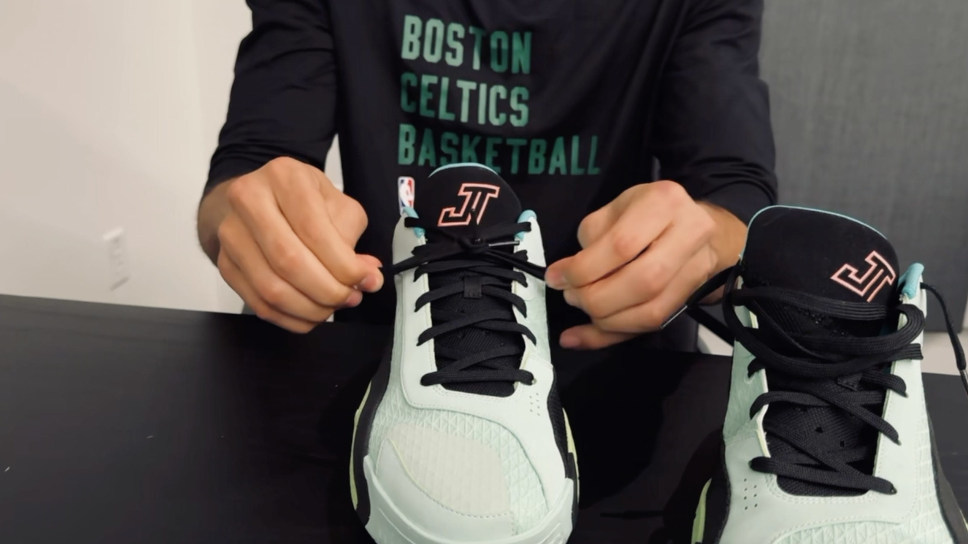 Jayson Tatum ties his green Jordan Brand sneakers.