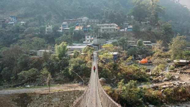 A trekker on a hanging bridge in Nepal