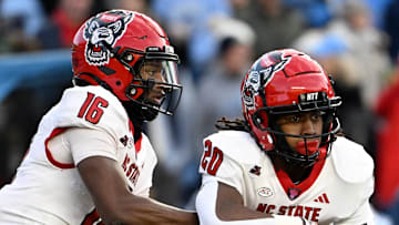 Nov 30, 2024; Chapel Hill, North Carolina, USA; North Carolina State Wolfpack quarterback CJ Bailey (16) hands the ball off to running back Hollywood Smothers (20) the ball in the first quarter at Kenan Memorial Stadium. Mandatory Credit: Bob Donnan-Imagn Images