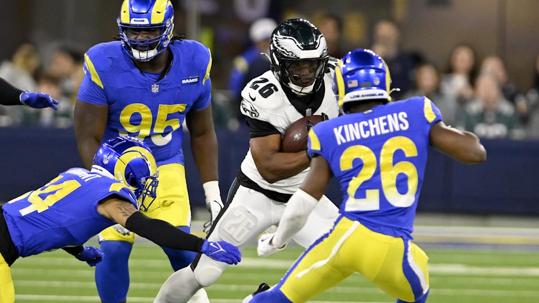 Nov 24, 2024; Inglewood, California, USA;  Philadelphia Eagles running back Saquon Barkley (26) runs against Los Angeles Rams cornerback Cobie Durant (left), and safety Kamren Kinchens (26) during the first half at SoFi Stadium. Mandatory Credit: Alex Gallardo-Imagn Images