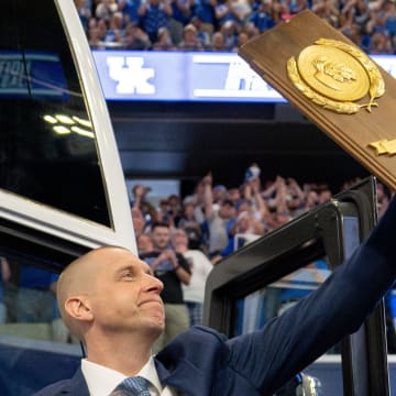 Mark Pope exits the bus with holding a trophy as he enters Rupp Arena greeting thousands of fans for his introductory press conference on Sunday, April 14, 2024.