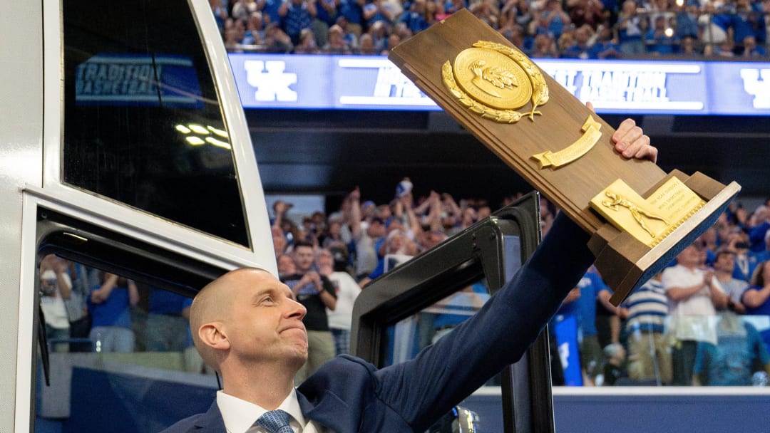 Mark Pope exits the bus with holding a trophy as he enters Rupp Arena greeting thousands of fans for his introductory press conference on Sunday, April 14, 2024.