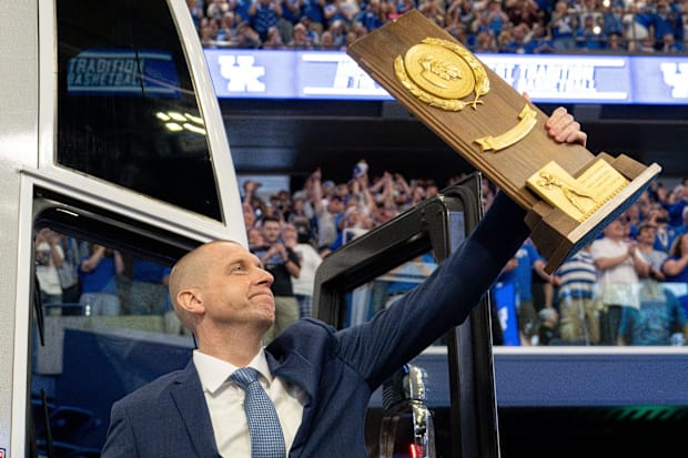 Pope exits the bus with the national championship trophy as he enters Rupp Arena in April.